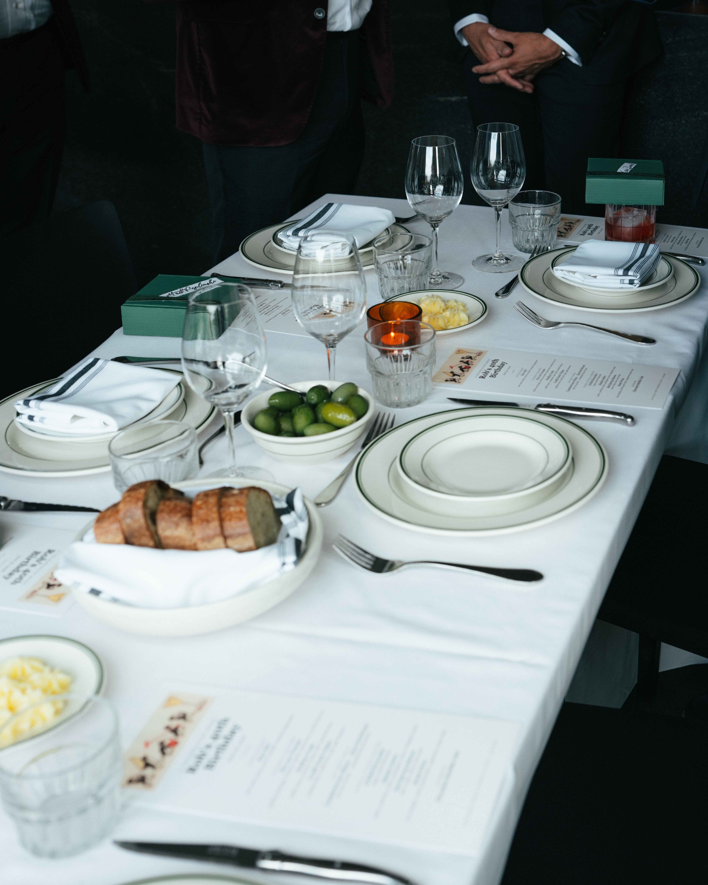 A long table set with linen, glassware and printed menus for a private dinner